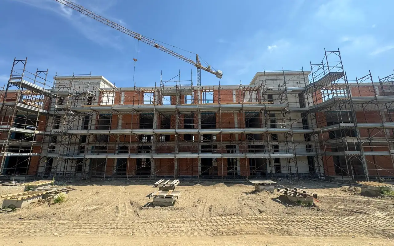 Il cantiere della Residenza Gli Orti durante i lavori: struttura in costruzione, gru e ponteggi.